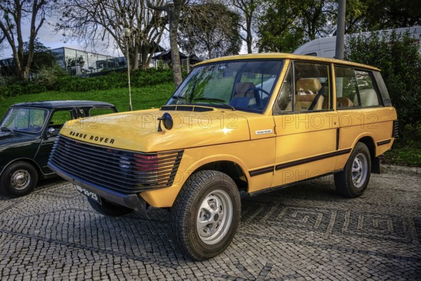 Lisbon, Portugal, Jan 20, 2024: A classic yellow Land Rover Range Rover car with extra front protection detailing parked on a cobblestone road near green park, Europe