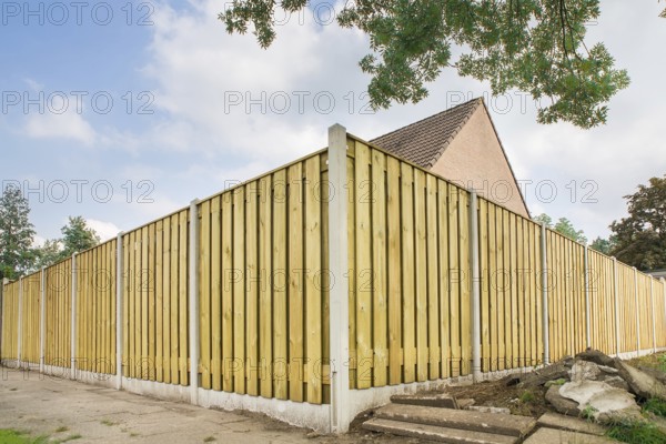 New wooden fence as corner around garden of home