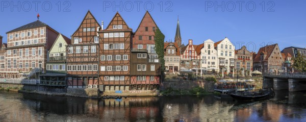 Panoramic photo Lüneburg harbour at the Illmenau with old Hanseatic wooden boats, surrounding buildings of the medieval old town and Lünertorstraße bridge, Lüneburg, Lower Saxony, Germany, Europe