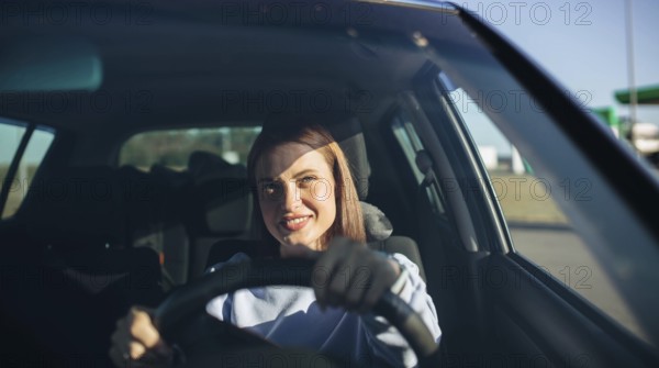 Woman smiling while confidently driving a car in daylight
