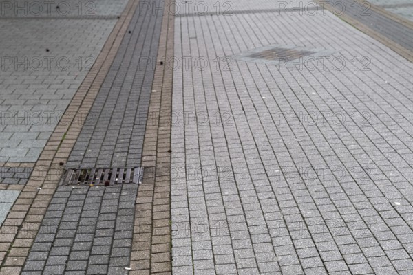 Deserted paved pedestrian zone with gully cover