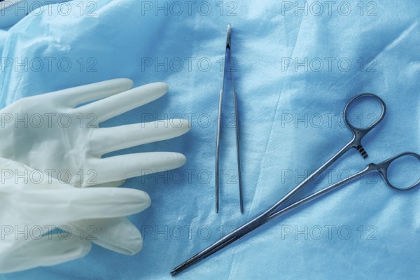 Surgical tools and gloves on blue cloth, showing readiness for medical procedures