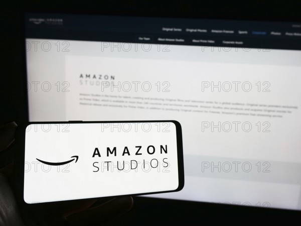 Stuttgart, Germany, 11-08-2023: Person holding smartphone with logo of US film and television production company Amazon Studios in front of website. Focus on phone display, Europe