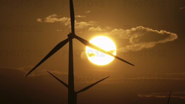 Beautiful sunrise dawn landscape with windmills or wind turbine on wind farm in rotation to generate electricity energy