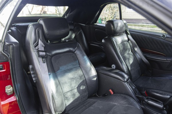 Spacious car interior with black leather seats and headrest, bathed in sunlight