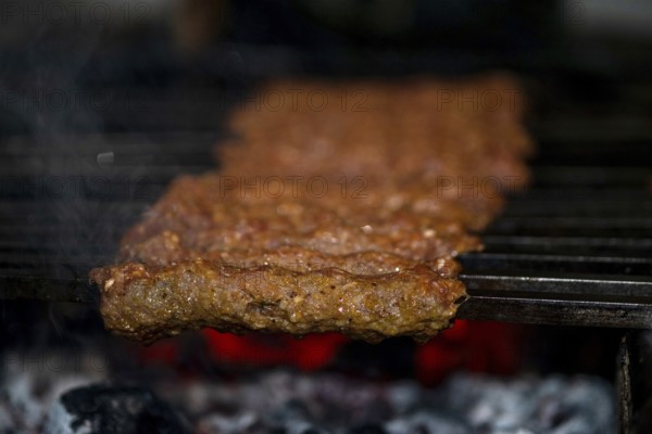 Making Spicy seekh kebabs are being grilled on burning charcoal in barbeque at a dinner party at night
