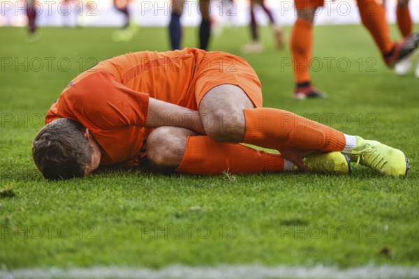 The injured footballer lies on the pitch.