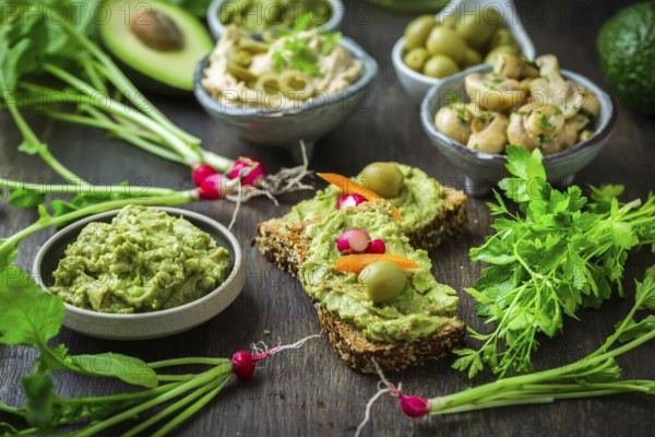 Wholemeal bread with avocado spread and vegetables on wooden kitchen table