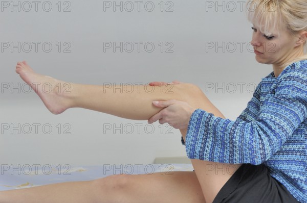 Legs, A woman sitting indoors examining her knee, wearing a blue patterned sweater