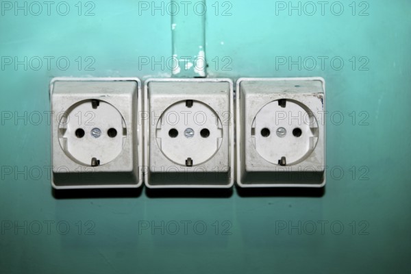 Aged electric plug socket dirty over green wall