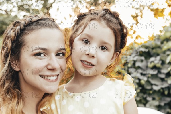 Cute little redhead girl and happy young mother with similar braided hairdo hugging together