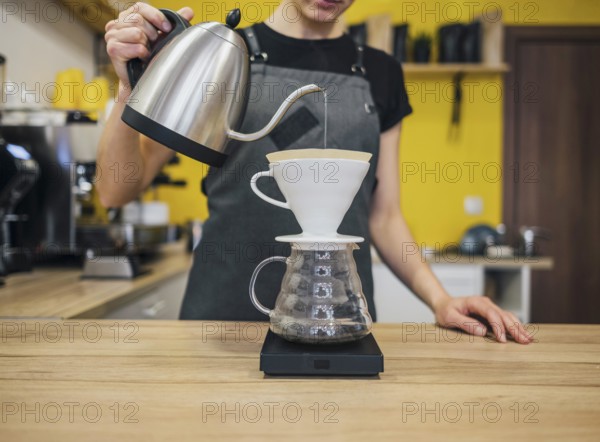 Front view female barista pouring hot water coffee filter