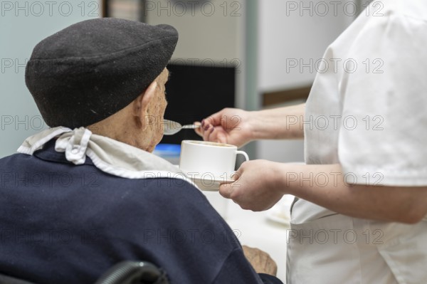 Senior man getting fed by carer in nursing home. graphy