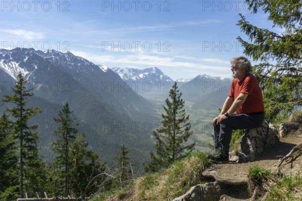 Hiker, senior citizen, 66, resting on the summit of the Osterfeuerkopf with a view of the Zugspitze, Eschenlohe, Estergebirge, Upper Bavaria, Bavaria, Germany, Europe