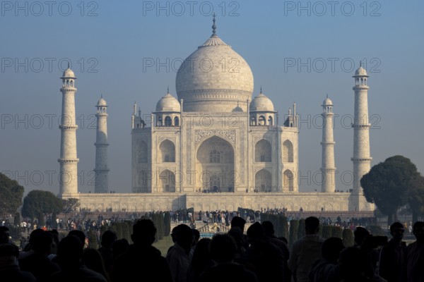 Taj Mahal, the mausoleum built for Mumtaz Mahal by her husband, the Mughal emperor, Shah Jahan. Wonder of the World, a UNESCO World Heritage Site, famous landmark and tourist attraction. View from the gateway with visitors watching and photographing. Winter morning light, clear blue sky. Agra, Uttar Pradesh, India, Asia