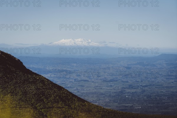 Snow-capped mountains on the horizon, hills in the foreground and blue sky, Mount Taranaki, New Zealand, Oceania