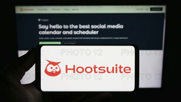 Stuttgart, Germany, 01-13-2023: Person holding smartphone with logo of Canadian software company Hootsuite Inc. on screen in front of website. Focus on phone display, Europe