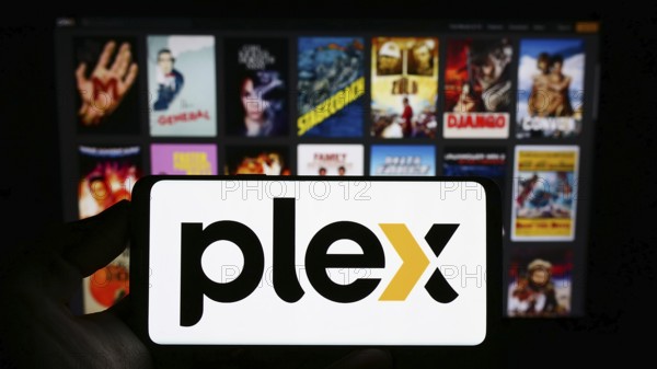 Stuttgart, Germany, 01-14-2023: Person holding mobile phone with logo of American video streaming company Plex Inc. on screen in front of web page. Focus on phone display, Europe