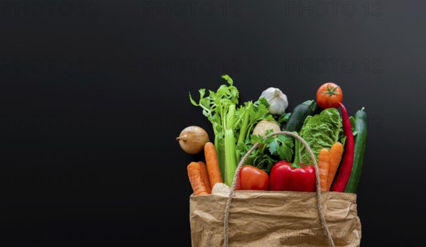 top view of fresh organic vegetables bought on weekly market in brown paper bag against dark table background