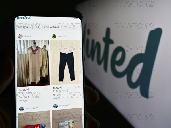 Stuttgart, Germany, 03-17-2024: Person holding cellphone with webpage of online secondhand marketplace company Vinted in front of logo. Focus on center of phone display, Europe