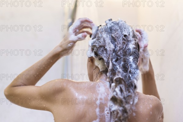 Young woman washing hair in shower