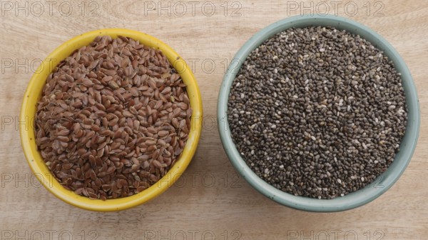 Chia Seeds (Salvia hispanica) vs Flaxseeds (linseeds) in Bowls on Wooden Background, Flat Lay Photo
