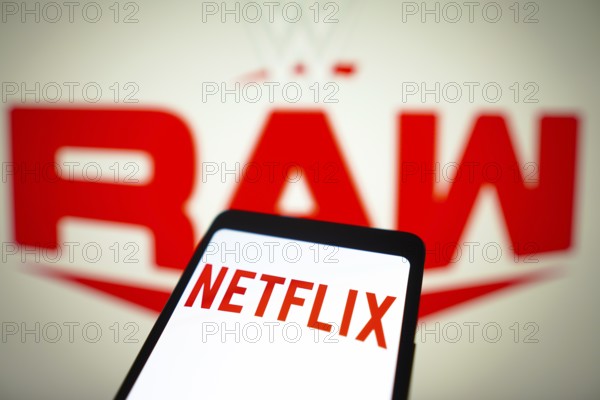In this photo illustration, the Netflix logo is displayed on a smartphone screen and WWE Raw logo in the background