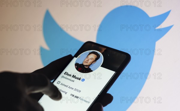 In this photo illustration, the Elon Musk Twitter account displayed on a smartphone screen and Twitter logo displayed on a screen in the background