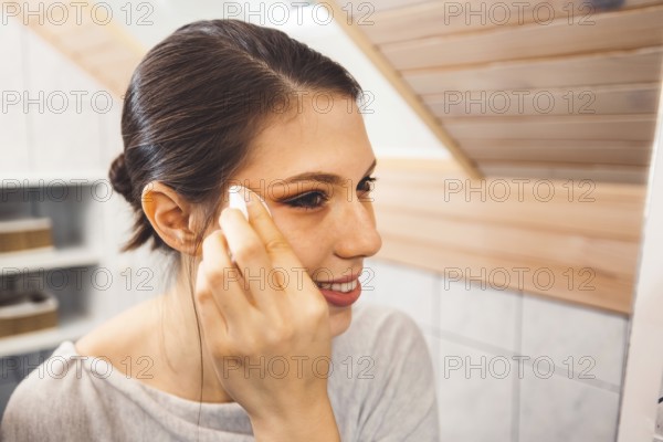 Beautiful young woman cleaning her face, removing make up with a cotton pad and micellar water. Skin care and beauty. Young beautiful woman cleaning her face.