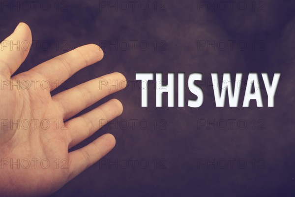 Hand making welcome gesture with THIS WAY wording