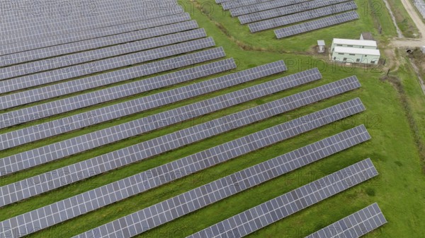 Rows of solar panels covering a large field with an overcast sky