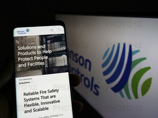 Stuttgart, Germany, 03-12-2022: Person holding cellphone with webpage of company Johnson Controls International plc (JCI) on screen with logo. Focus on center of phone display, Europe
