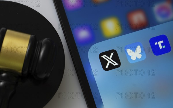A close up of an iPad screen displaying the Truth Social, bluesky and X app alongside a judge's gavel