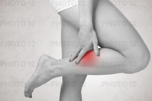 Female with pain in her lower leg, isolated in grey
