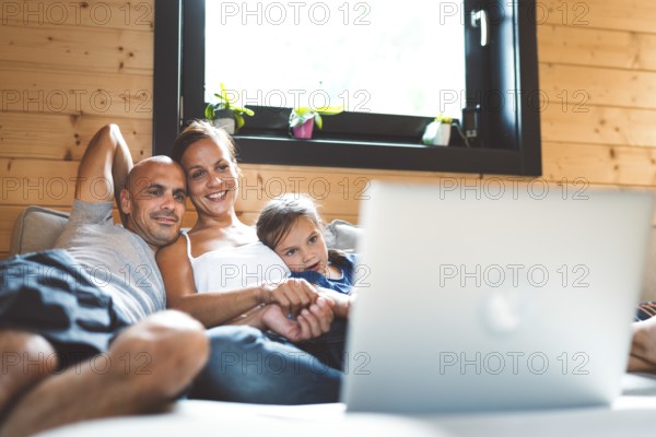 Young family with a girl, spending time at home on the weekends. Loving family resting on the couch, playing, watching television