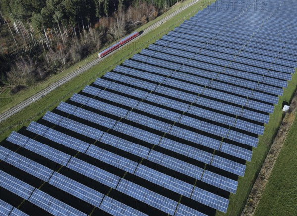 Red local railway runs on a non-electrified railway line next to a solar park through a green landscape, drone shot, Upper Bavaria, Bavaria, Germany, Europe
