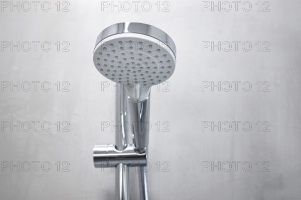 Shower head on a gray microcement wall of a modern bathroom