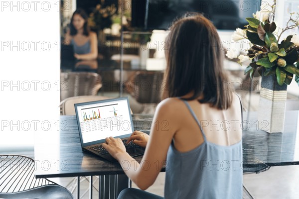 Back view of young businesswoman working on laptop at modern home. freelance concept