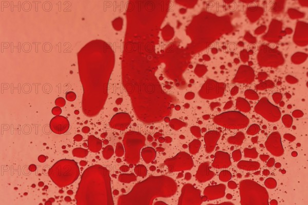 Macro of drops of red food color on cooking oil with back light through red photography gel