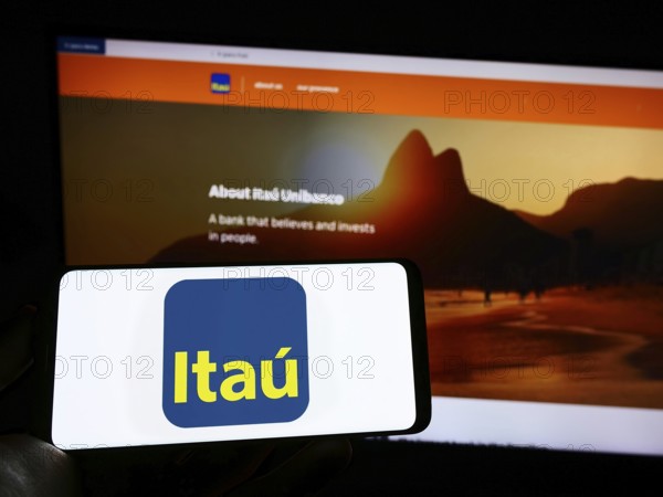 Stuttgart, Germany, 10-14-2022: Person holding cellphone with logo of Brazilian company Itau Unibanco Holding SA on screen in front of business webpage. Focus on phone display, Europe