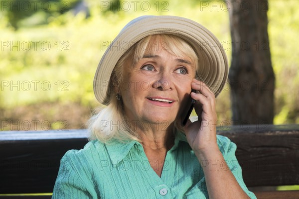 Senior woman on the phone. Mature lady in a hat. Stay in touch with relatives. Cheap calls abroad