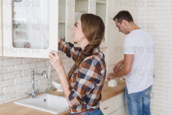 Young positive couple making tea kitchen home