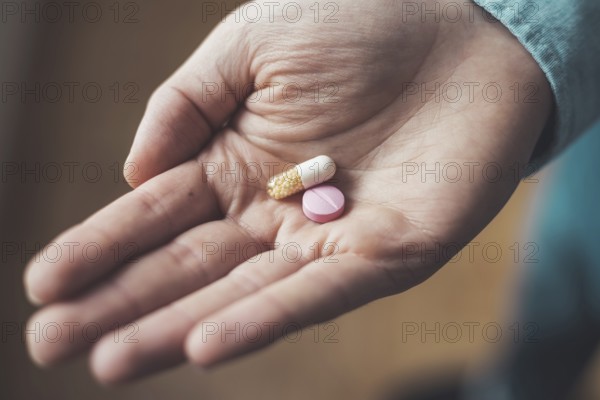 Male hand holding drug or vitamin pill in