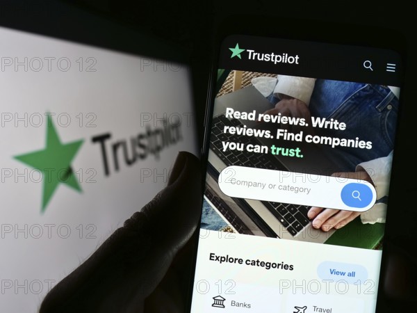 Stuttgart, Germany, 01-13-2023: Person holding cellphone with webpage of review platform company Trustpilot Group plc on screen with logo. Focus on center of phone display, Europe