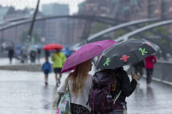 Symbolic picture weather, heavy rain in summer, thunderstorm, thunderstorm, tourists with umbrellas on the way in the rain at the jetties in the harbour of Hamburg, Germany, Europe