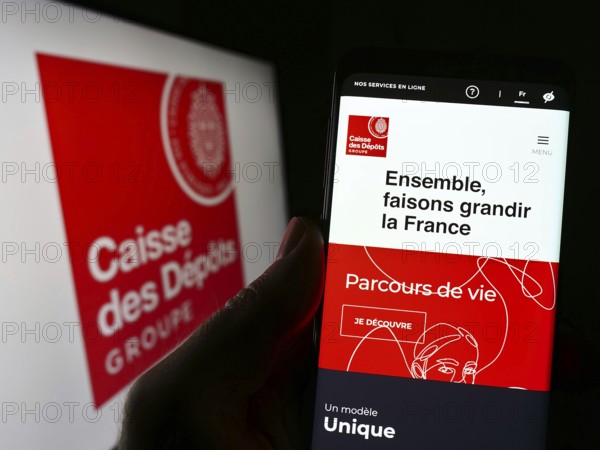 Stuttgart, Germany, 03-12-2023: Person holding smartphone with webpage of Caisse des Depots et Consignations (CDC) on screen in front of logo. Focus on center of phone display, Europe