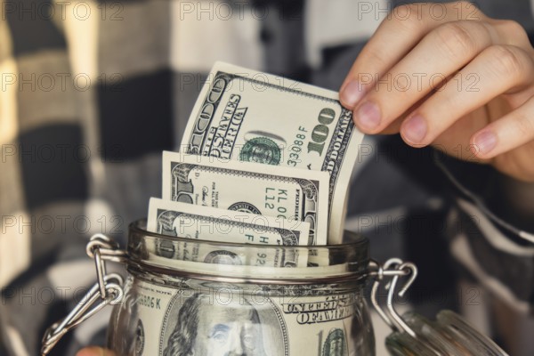 Dollar banknote saving money in glass jar. Unrecognizable woman moderate consumption and economy Collecting money. Tips. Business, finance, saving, banking and people concept. Extra money, passive income. Saving for travel, crisis, house, car, education, retirement