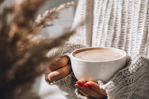 Pampas grass and female hand holding white cup with coffee. Drinking Cappuccino in the breakfast morning at home. Aesthetics. Cozy home