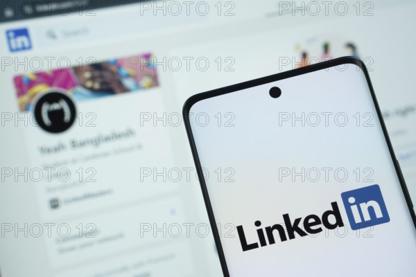Dhaka, Bangladesh - 17 March 2025: The logo of the linked in is displayed on a smartphone screen, and the website linked in is visible on a computer screen in the background