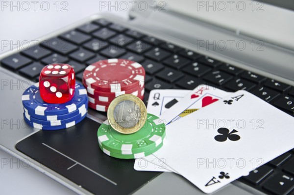 Playing cards, casino chips and Euro coin on a laptop keyboard symbolizing online gambling